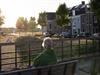 mevrouw, zit op bankje, kijkt naar de omgeving, bomen, woonwijk