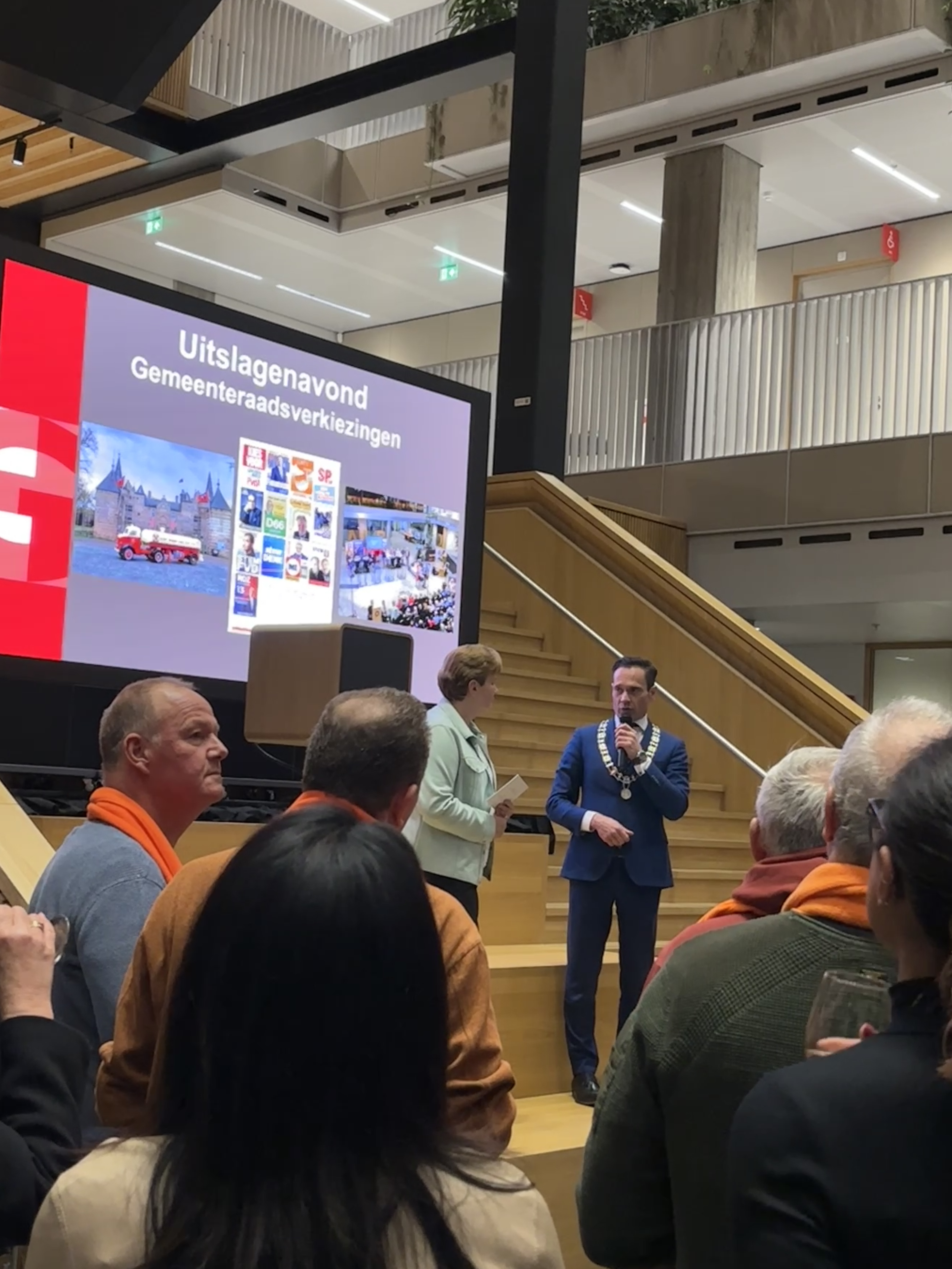 Burgemeester Sjoerd Potters staat samen met Lia Stroop op het podium tijdens de uitslagenavond van de gemeenteraadsverkiezingen 2026