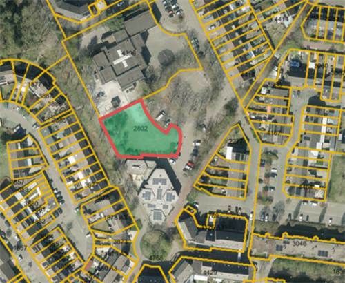 Luchtfoto van de locatie van tijdelijke huisvesting met een groen gemarkeerd gebied dat met een rode lijn is gearceerd het plangebied aangeeft. De omliggende woningen en percelen zijn met gele lijnen weergegeven.